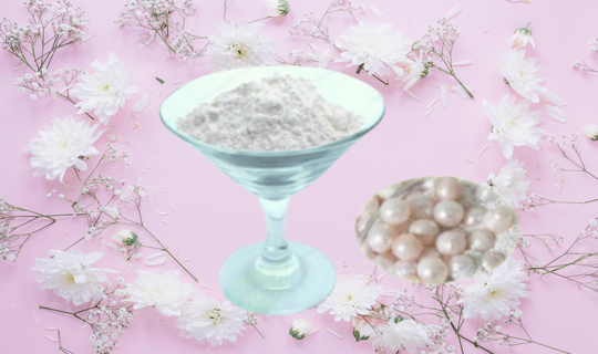 A wine glass filled with pearl powder and pearls in the powder alongside, showcased in a lavender background with beautiful white flowers framed around.