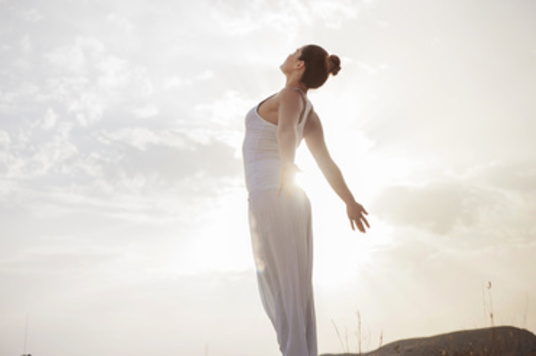Beautiful brunette woman standing on a hill stretching her muscles for better flexibility.