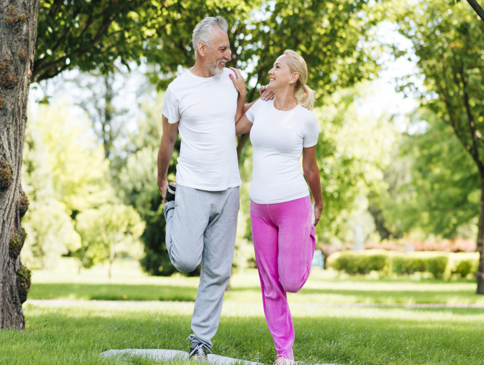 Husband and wife in the park, looking and smiling at one another while they exercise together.